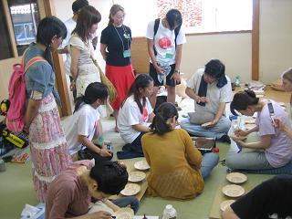 和室で指導を受けながら留学生や学生たちがお皿の絵付けをしている写真