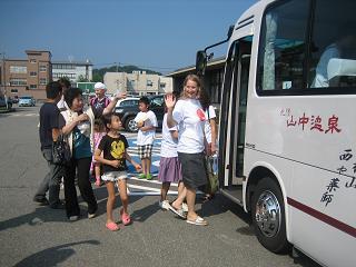 留学生が手を振りながらバスに乗ろうとしている写真