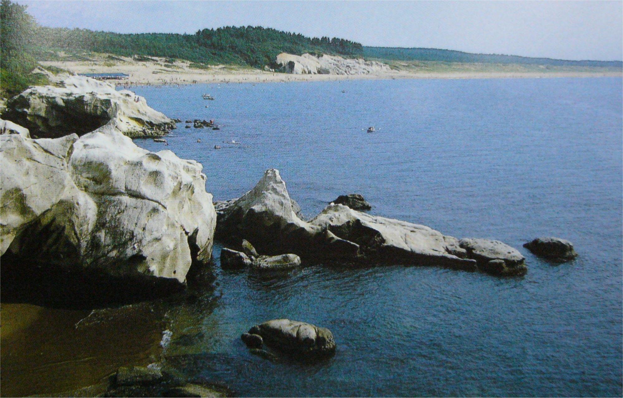 手前は岩が連なり奥は砂浜が広がっている国定公園加賀海岸の写真