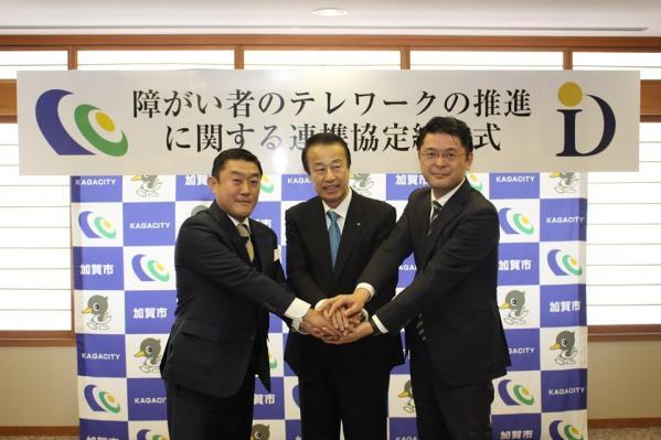 杉本 大祐様と内田 陽介様と市長が手を合わせている写真