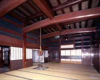 天井に大きな梁があり、畳の間に囲炉裏がある日本家屋の写真