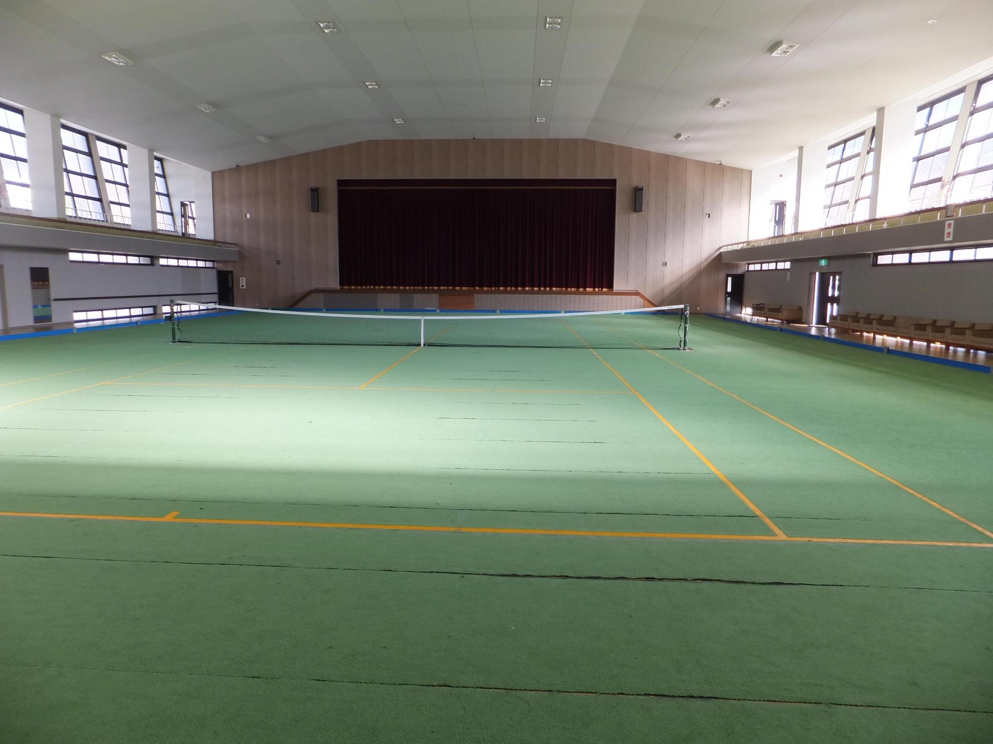 施設内の広いホールでテニスコートが設置されている写真