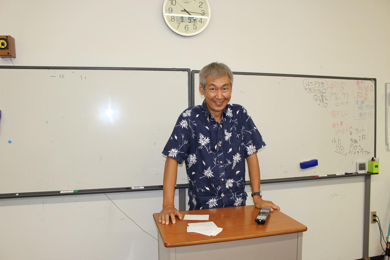 ホワイトボードの前にある教壇に立っている久保田雅裕さんの写真