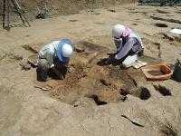 2人が手作業で地面を発掘している写真